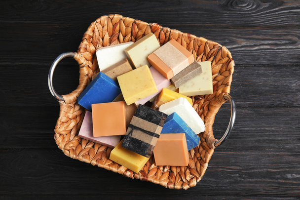 Many different handmade soap bars in wicker basket on table, top view - 写真・画像
