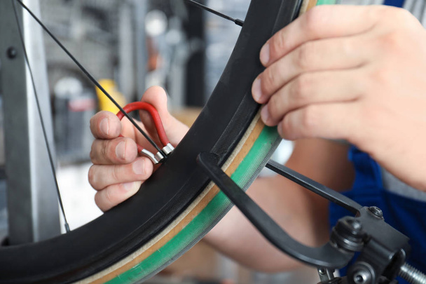 Professional mechanic repairing bicycle in modern workshop, closeup - Photo, image