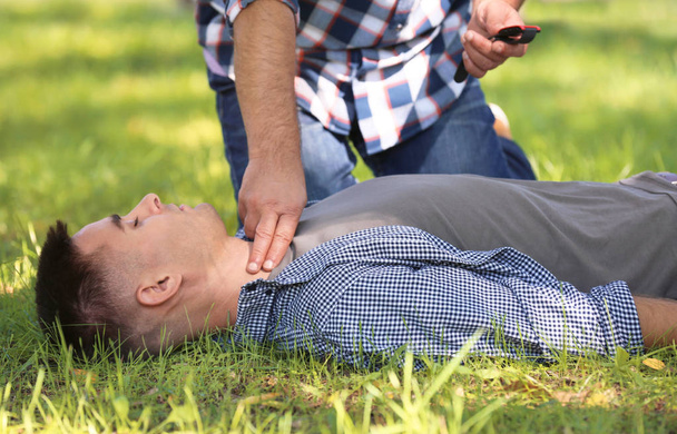 Passersby helping unconscious man outdoors. First aid - Foto, Imagen