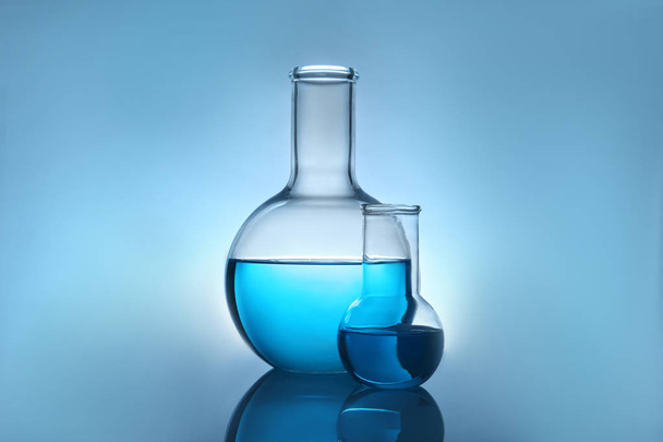 Flasks with liquid on table against color background. Laboratory analysis - Photo, Image