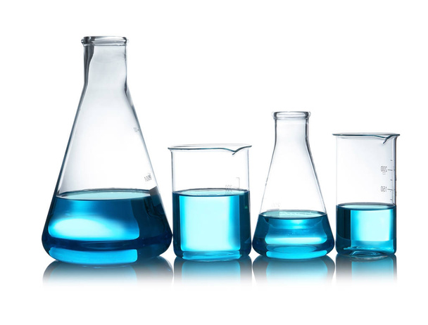 Artículos de vidrio de laboratorio con líquido sobre la mesa sobre fondo blanco. Análisis químico
 - Foto, Imagen