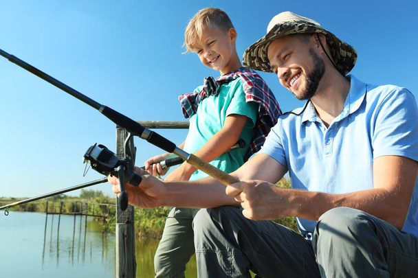 Father and son fishing together on sunny day - Foto, Imagem
