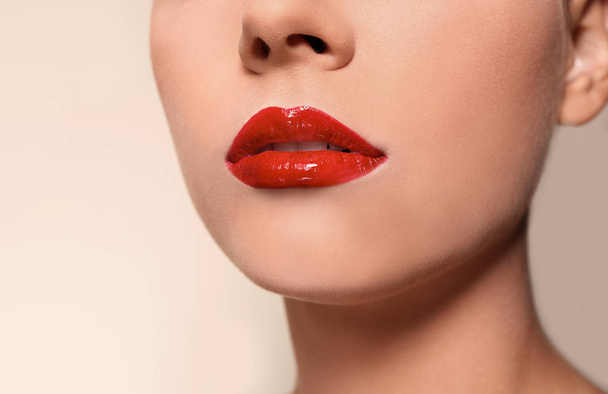 Beautiful young woman with red glossy lips on color background, closeup - Foto, Imagem