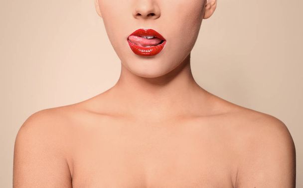 Beautiful young woman with red glossy lips on color background, closeup - 写真・画像