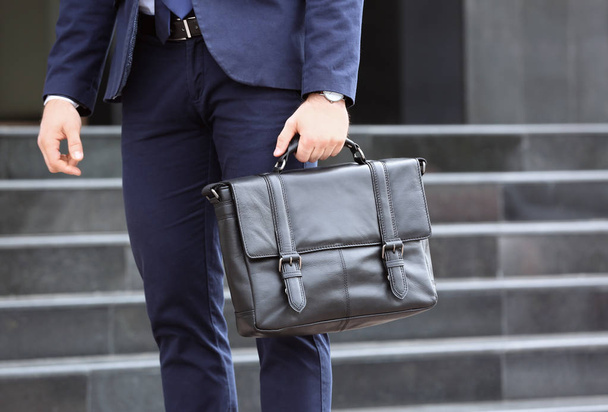 Businessman with black briefcase in hand outdoors - Фото, изображение
