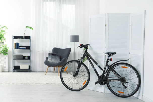 New bicycle near folding screen in stylish room interior - Foto, afbeelding
