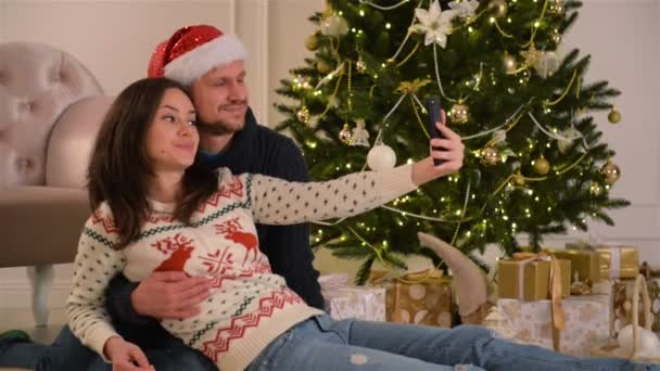 Happy Young Couple Taking Selfie In Decorated For Christmas Room. Happy New Year Concept. Lovely Family. - Video