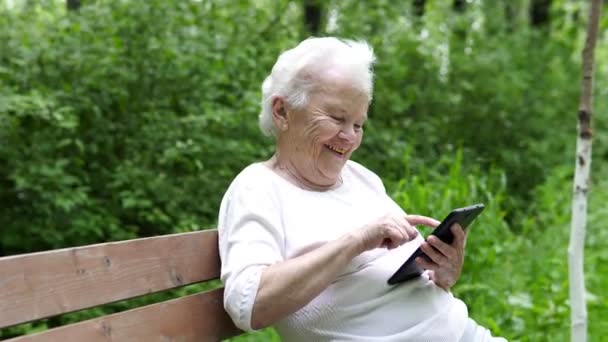 stará babička se dívá na internetu smartphone - Záběry, video