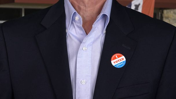 Старший кавказький чоловік у формальному одязі з наклейкою для голосування
 - Фото, зображення