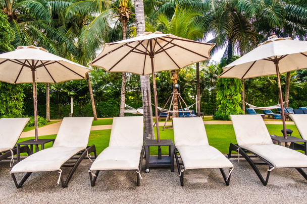 Mooie luxe buitenzwembad met parasol en stoel in hotel en resort voor reizen en vakantie - Foto, afbeelding