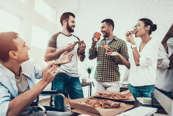 Young People Have Lunch with Pizza in Office. Teamwork in Office. Young Worker. Sitting Man. Box with Pizza. Young Girl in Glasses. Young Worker. Manager on Break. Man on Wheelchair. - Фото, изображение