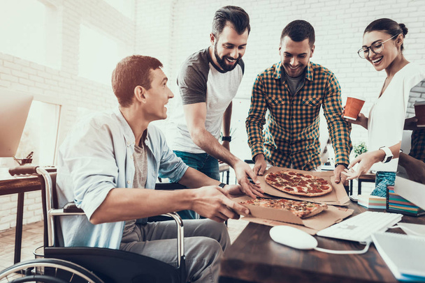 Young People Have Lunch with Pizza in Office. Teamwork in Office. Young Worker. Sitting Man. Box with Pizza. Young Girl in Glasses. Young Worker. Manager on Break. Man on Wheelchair. - Foto, Bild