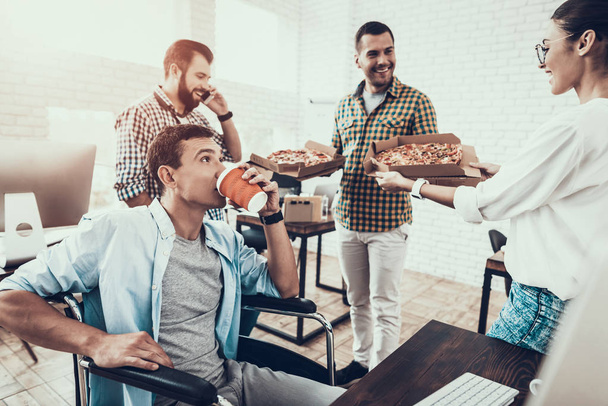 Young People Have Lunch with Pizza in Office. Teamwork in Office. Young Worker. Sitting Man. Box with Pizza. Young Girl in Glasses. Young Worker. Manager on Break. Man on Wheelchair. - Фото, изображение