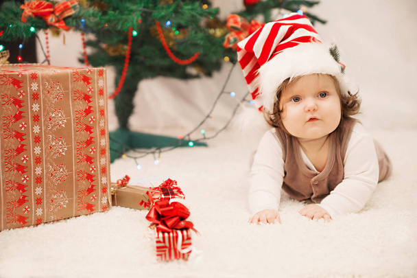 カーペットの上のクリスマスの帽子の赤ん坊 - 写真・画像