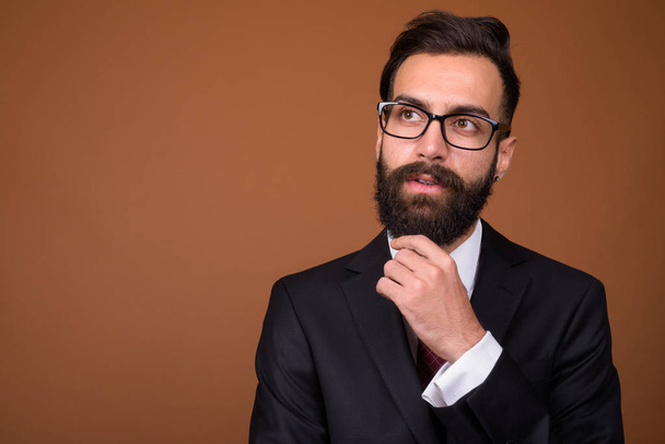 Young handsome bearded Persian businessman against brown backgro - Photo, Image