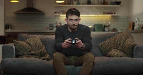 Молодий чоловік сидить на дивані граючи у відеоігри
. - Кадри, відео