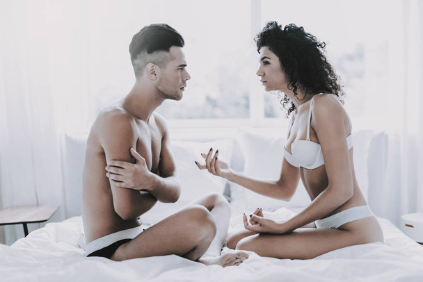 Young Unhappy Couple Arguing in Bed at Home. Handsome Man and Beautiful Woman having Conflict in Bedroom. Frustrated Couple having Problems. Relationship Difficulties and Family Concept - Fotó, kép