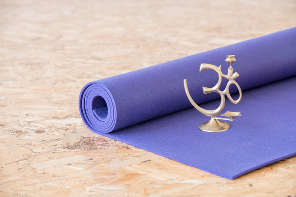 Ом знак медитації на фіолетовому килимку йоги в тренувальному залі
 - Фото, зображення