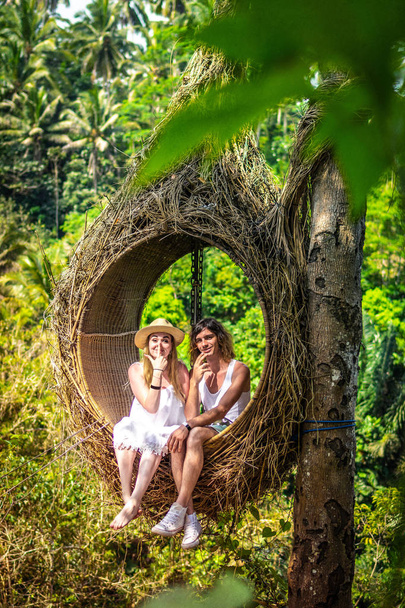 Traveler honeymoon couple in decorative nest the jungle of Bali island, Indonesia. Couple in the rainforest. - Фото, зображення