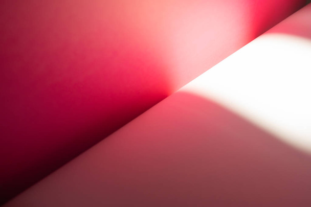 Ροζ και λευκά φύλλα χαρτόνι με ηλιοφάνεια αντηλιά. Η κλίση του φωτός και της σκιάς. Διαγώνια κάμψη γραμμή - Φωτογραφία, εικόνα