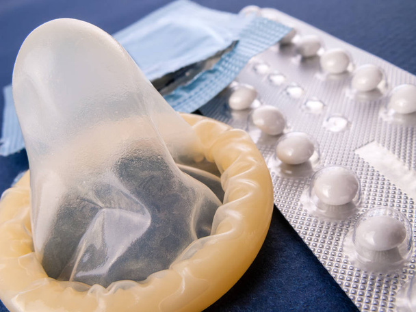 противозачаточные таблетки и развернутый презерватив
 - Фото, изображение