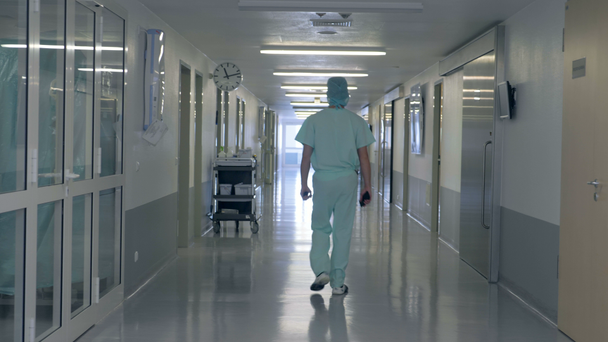 Een man walking in een hal van de kliniek. Persoon in de uniforme wandelingen van de arts in een ziekenhuis-gebouw. - Video