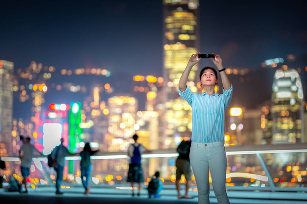 Jovem mulher usando smarphone na rua da cidade de Hong Kong à noite
 - Foto, Imagem