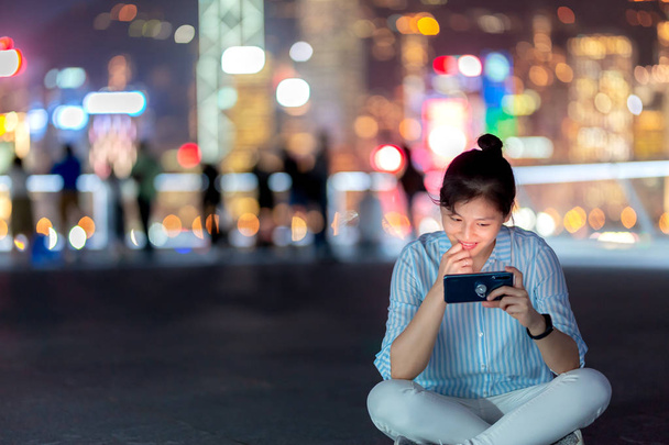 Νεαρή γυναίκα χρησιμοποιώντας smarphone στο δρόμο τη νύχτα της πόλης Χονγκ Κονγκ - Φωτογραφία, εικόνα