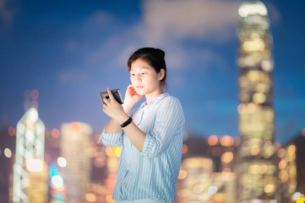 Jovem mulher usando smarphone na rua da cidade de Hong Kong à noite
 - Foto, Imagem