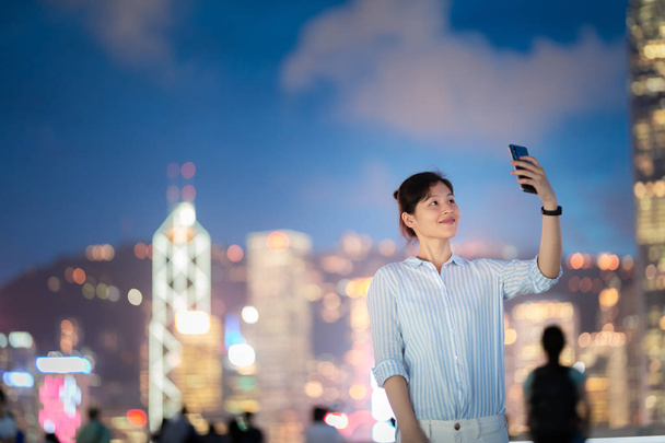 junge Frau benutzt nachts Smartphone in der Straße von Hongkong - Foto, Bild