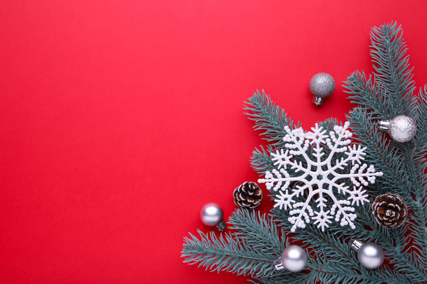Christmas decoration. Fir-tree branch with balls, bumps, snowflake on a red background - Фото, зображення