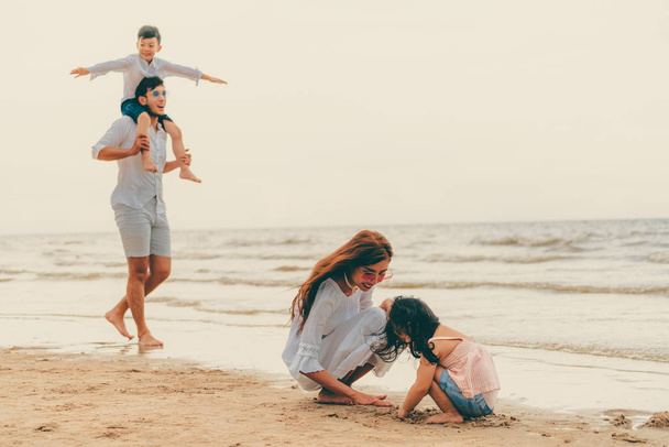 Happy family of father, mother and kids goes vacation on a tropical sand beach in summer. - Fotó, kép