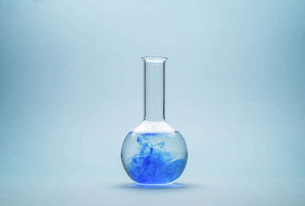 Round-bottom flask over blue background - Zdjęcie, obraz