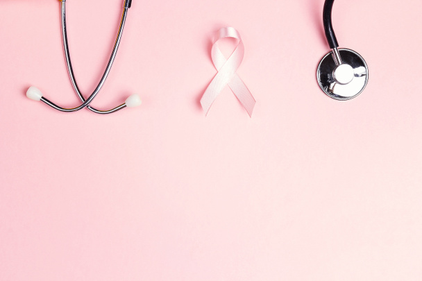 Pink ribbon and stethoscope on pink background wiyh copy space. Breast cancer awareness symbol. October awareness month campaign. - 写真・画像