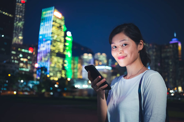 Νεαρή γυναίκα χρησιμοποιώντας smartphone στην πόλη - Φωτογραφία, εικόνα
