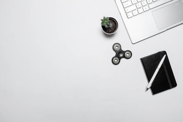 Minimal modern workspace. Composition with laptop, cactus, notebook with pen and fidget spinner on white desk. Top view, flat lay. - Fotoğraf, Görsel