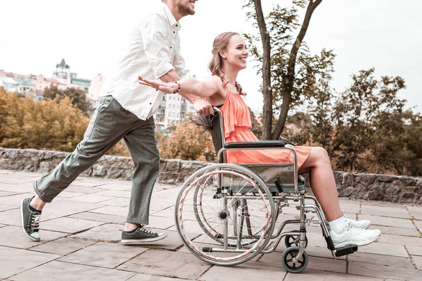 Disabled girl feeling special while boyfriend pushing her wheelchair - Photo, image