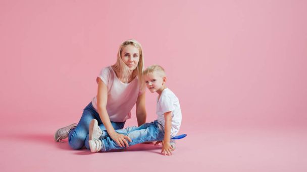 Positive young mother with a young son. Beautiful blonde with her baby on a skateboard - Fotó, kép