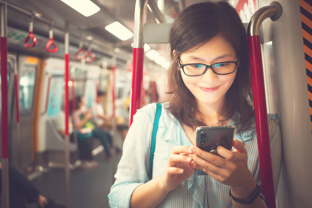 Nuori nainen käyttää älypuhelinta junan sisällä
 - Valokuva, kuva