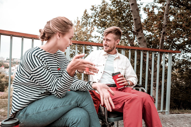 Emotional woman sitting next to disabled man and talking to him - Zdjęcie, obraz