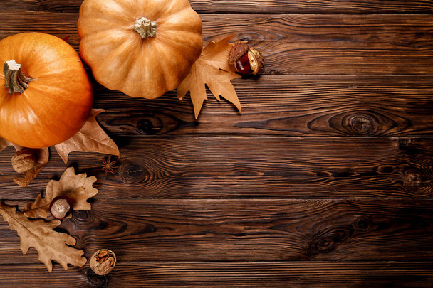 Thanksgiving background concept. Local produce pumpkin, chestnut, autumn dry oak & maple leaves and anise for decoration on wood textured table. Close up, copy space, top view, flat lay. - Photo, Image