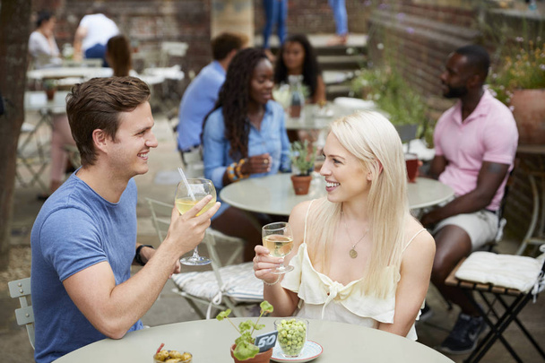 Couple Sitting At Table In Pub Garden Enjoying Drink Together - Photo, Image