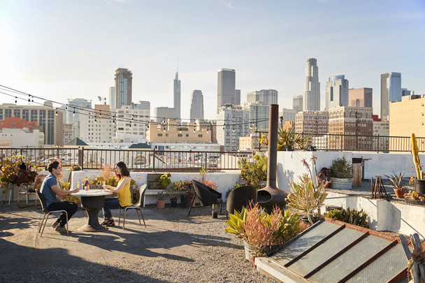 Couple Drinking Wine And Making Toast On Rooftop Terrace With City Skyline In Background - Foto, Imagen