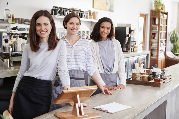 Three female coffee shop owners behind counter smiling - 写真・画像