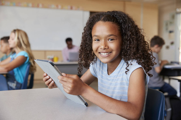 Girl using tablet in school class smiling to camera  - Fotó, kép
