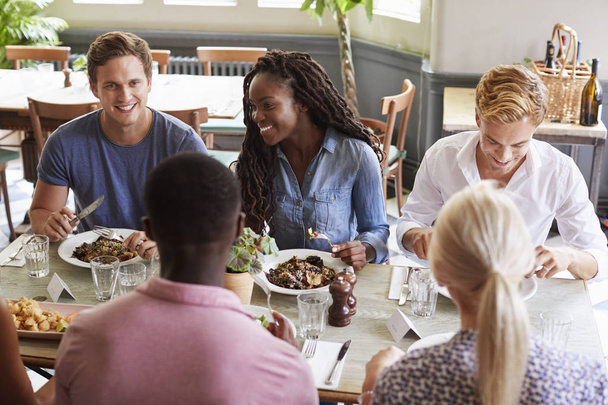 Group Of Friends Sitting At Table In Restaurant Enjoying Meal Together - Fotoğraf, Görsel