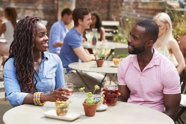 Couple Sitting At Table In Pub Garden Enjoying Drink Together - Foto, imagen
