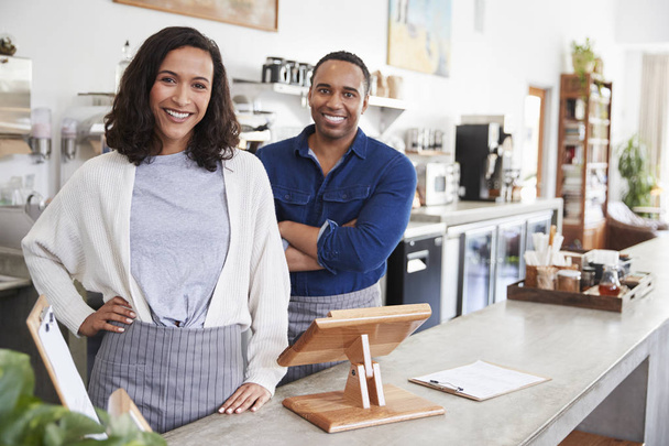 Mixed race couple behind counter at coffee shop - Fotó, kép