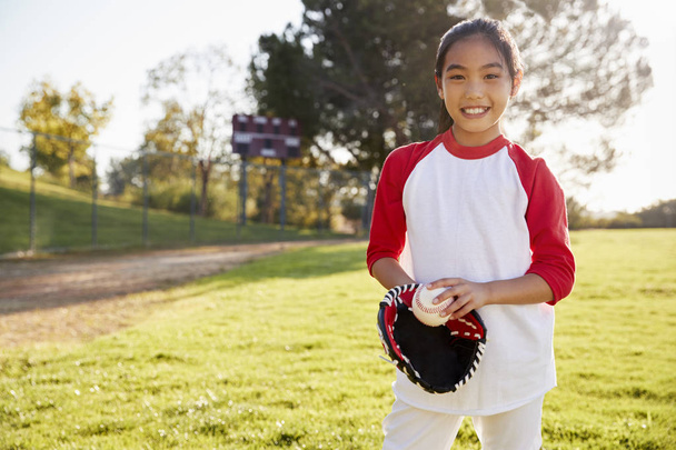 Chinese schoolgirl holding baseball and mitt smiling - Fotoğraf, Görsel