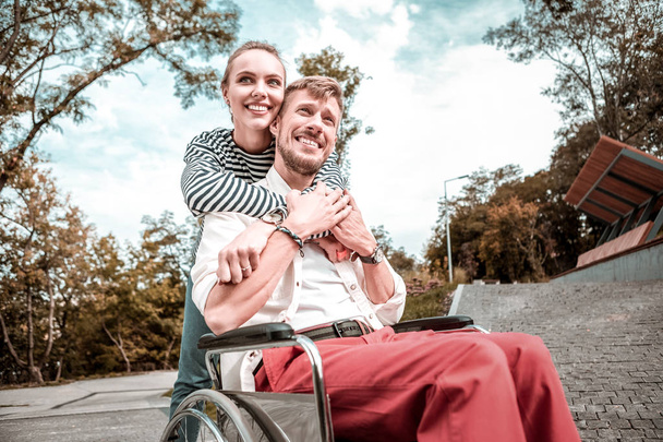 Positive woman hugging her disabled boyfriend and making him happy - Fotoğraf, Görsel